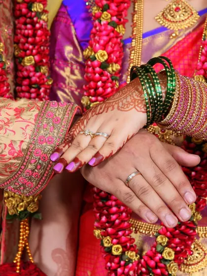 A beautiful shot of the couple's hands, displaying their rings, against the backdrop of their wedding garlands.