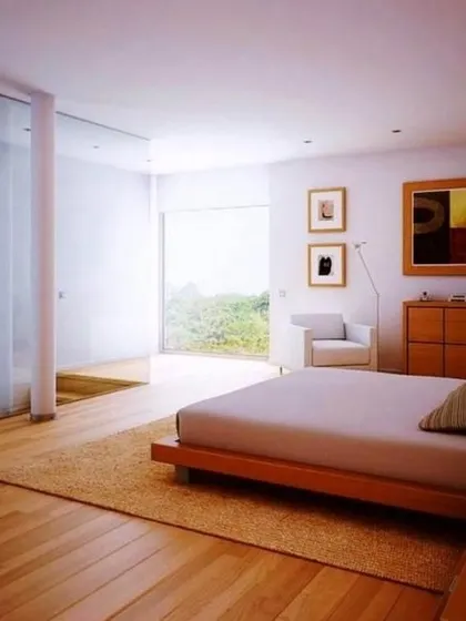 This bright and airy bedroom uses a light natural wood floor to enhance the sense of space and tranquility. It pairs perfectly with the minimalist furniture and large window, creating a serene retreat.