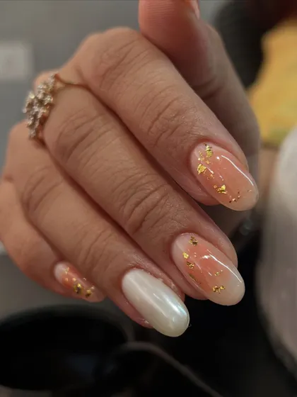 An ombré nail set with a twist. We combined a peachy ombré with gold flakes and a solid pearl chrome accent nail.