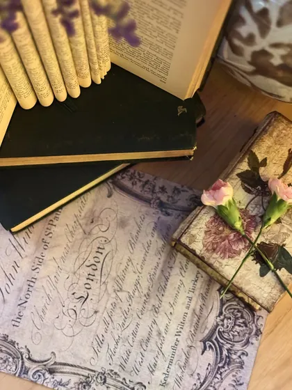 A beautifully styled detail shot with vintage books, calligraphy prints, and small floral touches, evoking a sense of romance and literary charm.