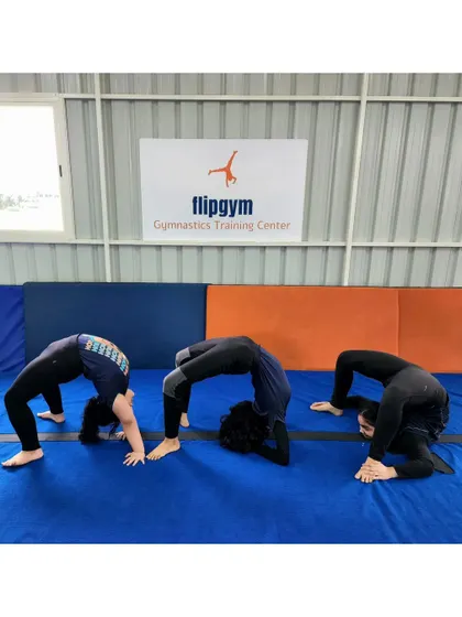 Three students demonstrate different variations of the back bridge, showcasing their individual levels of flexibility.