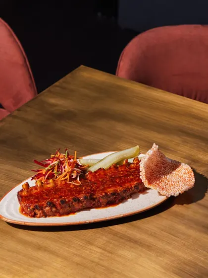 Our Baby Back Ribs, glazed in a spicy, sticky sauce and served with a side of pickled cucumber and sesame crisps. A modern take on a classic.