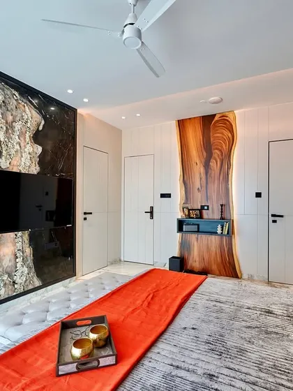 We love using natural materials in unexpected ways. This bedroom features a TV panel made from a unique stone slab and a desk area highlighted by a live-edge wood piece, creating a design that is both rustic and modern.