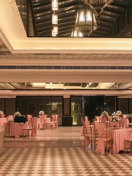 The indoor banquet hall decorated in sync with the outdoor wedding theme. Pink table linens and chair drapes continue the color story, creating a seamless transition for guests.