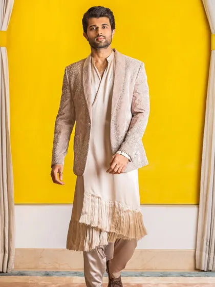 Vijay Deverakonda in a fusion look by Rohit Gandhi and Rahul Khanna. The embellished blazer worn over a draped, fringed kurta creates a unique silhouette that blends Western tailoring with Indian design.