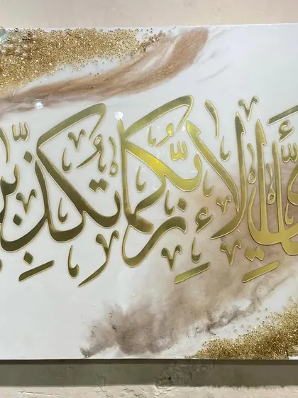 A close-up of the 'Fabi-ayyi ala-i rabbikuma tukaththiban' artwork, focusing on the crispness of the gold calligraphy against the soft, blended background.