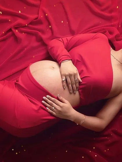 A confident and serene expression in this top-down portrait. Lying on a bed of red fabric, she looks directly at the camera, radiating peace.