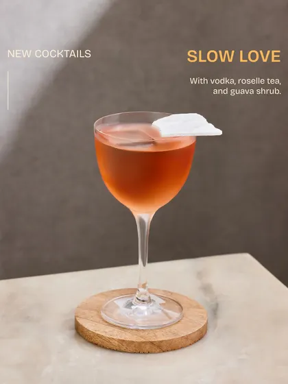 A study in elegance, the Slow Love cocktail. The delicate rice paper garnish floats atop a blend of vodka, roselle tea, and guava shrub, creating a visually stunning and romantic drink.