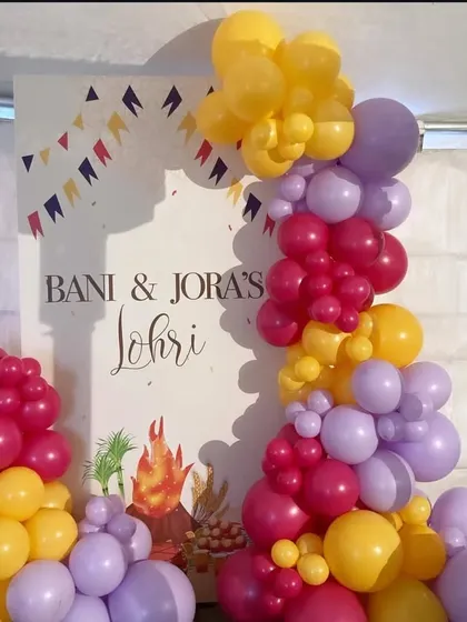 A modern take on Lohri decor, using colorful balloon pillars to frame a custom-printed backdrop for Bani and Jora's celebration.