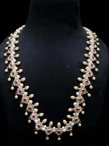 A long necklace or 'haar' made with ruby-colored stones and pearls. This classic combination is timeless and adds elegance to any saree or traditional dress.