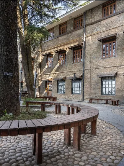 The completed outdoor classroom, nestled against a historic building at Woodstock School. The design uses natural contours and materials like river stones and reclaimed wood to create a serene learning environment.