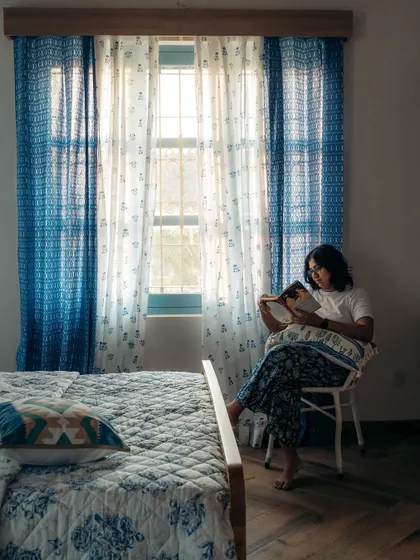 There's nothing like a quiet moment with a good book. I love how our blue-themed curtains and bedding create a serene and restful atmosphere in this bedroom, making it the perfect personal retreat.