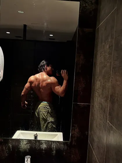 A mirror selfie from the back, capturing the full scope of my back and glute development. We build a complete physique.