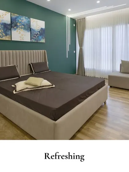 A refreshing bedroom featuring a bold green accent wall paired with modern, abstract art. The neutral furnishings and light wood flooring add warmth and balance, creating a space that is both stylish and calming.
