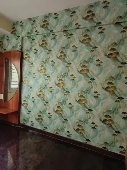 This bedroom wall is covered in a beautiful wallpaper featuring stylized flowers on a turquoise background. The pattern adds a cheerful and artistic touch, perfect for a personal sanctuary.