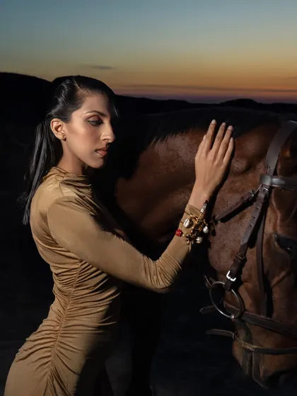 A side profile of a model gently touching a horse, showcasing elegant jewelry. The connection between the model and the animal adds a layer of emotion and storytelling to the photograph.