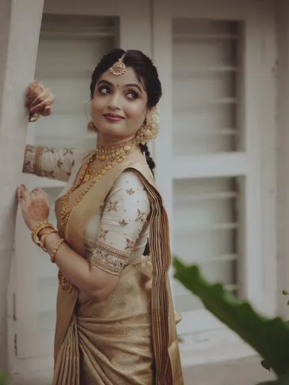 Another angle of a bride in a golden saree, showcasing her elegant posture and the fine details of her attire.