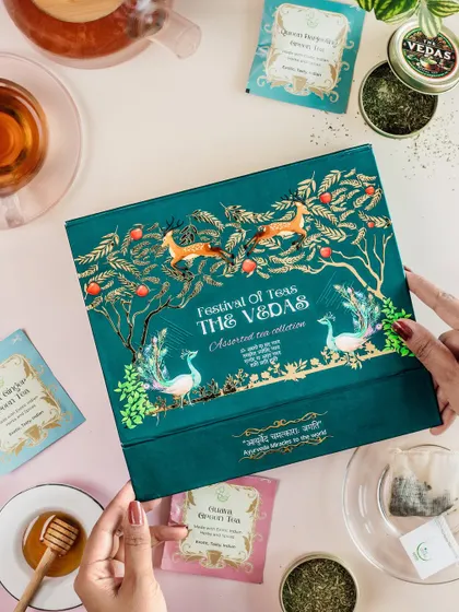 A lifestyle shot of a "Festival of Teas" gift box, styled with a cup of tea and honey.