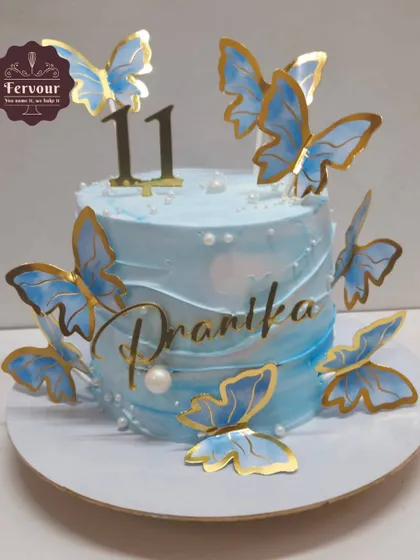 A lovely butterfly-themed cake in shades of blue. The design is simple yet beautiful, with delicate wafer paper butterflies that look like they're about to fly off the cake.