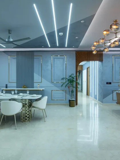 This dining space at SNN Clermont blends minimalist design with modern classic elements. The soft blue walls with gold-trimmed molding create a calm, luxurious base for shared meals.