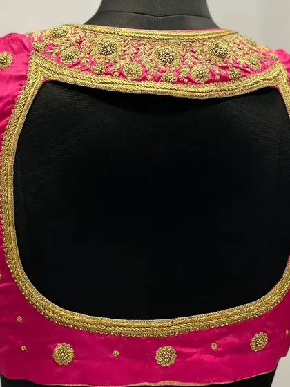 The back view of the pink blouse, showcasing the intricate gold embroidery that frames the open back.