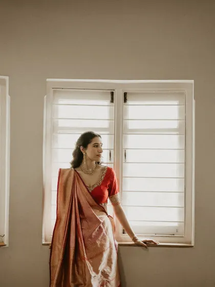 A portrait of the bride by the window, the natural light highlighting the beautiful texture of her silk saree.