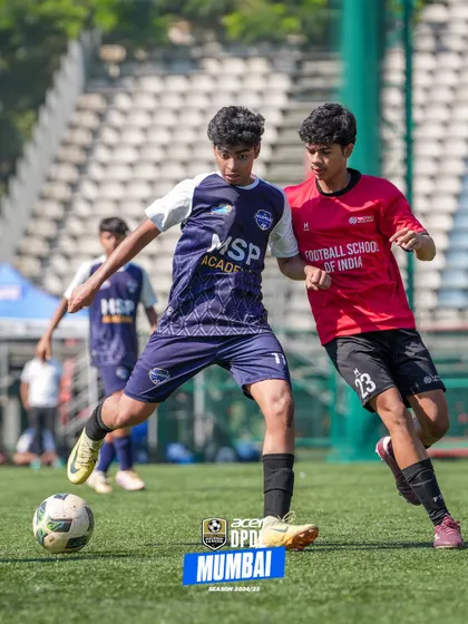 A player takes on a defender from the Football School of India, showing his competitive spirit.