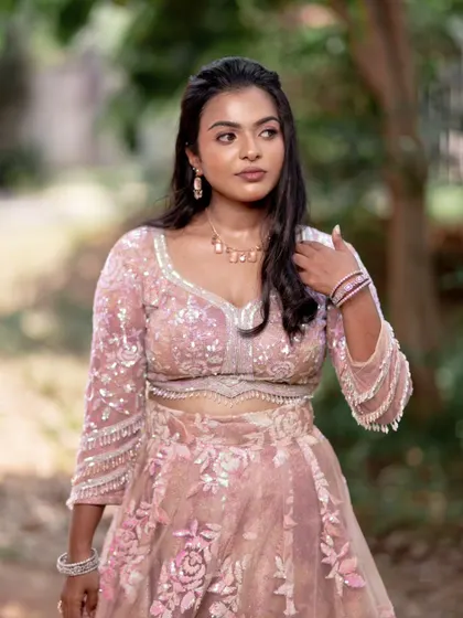 A model posing in a pink lehenga, showing off a subtle yet glamorous makeup look perfect for a reception.
