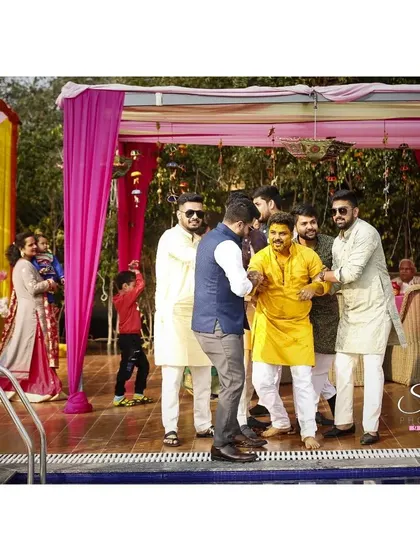 The friendly struggle before the inevitable pool dip. This candid shot is full of energy and laughter, showcasing the playful bond between the groom and his friends.