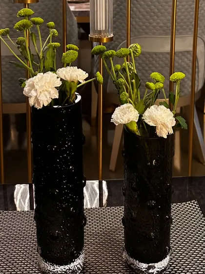 Chic and simple arrangements of white carnations and green button mums in textured black vases for a modern, high-contrast look.