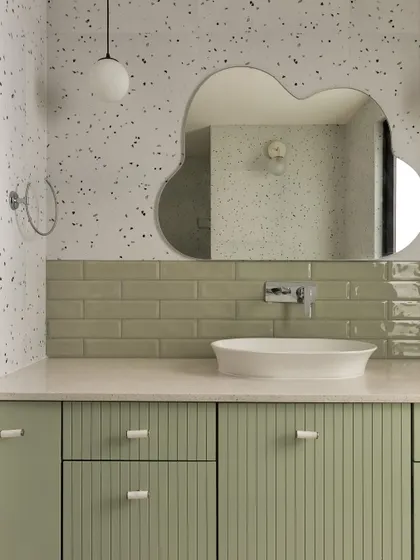 We designed this kids' bathroom with playful yet stylish elements. A sage green vanity with reeded doors is paired with a terrazzo-effect wall and a unique cloud-shaped mirror.