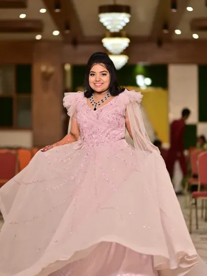 A twirl of happiness. This light pink ball gown with its flowing skirt and cape sleeves is perfect for a bride who wants to feel like a princess on her engagement day.