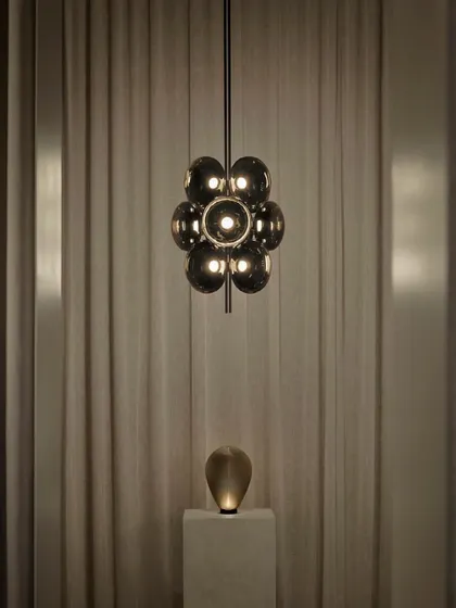 The Aeris light, inspired by the ethereal beauty of clouds. This fixture embodies softness and lightness through the repetition of sculptural, smoked glass forms, creating an ethereal centerpiece.