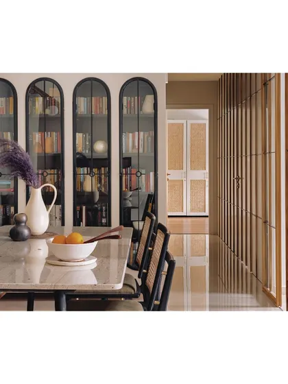 To maximize space and create a feature wall, we designed these arched, black-framed bookshelves. They provide ample storage for a large book collection while adding a strong graphic and architectural element to the dining area.