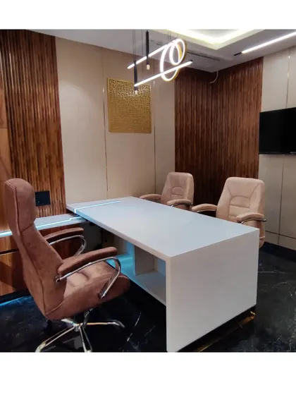 An angled view of Mr. Siraj's cabin, showing the clean lines of the white marble desk against the dark, polished floor and wood-paneled walls. The lighting is designed to be both functional and atmospheric.