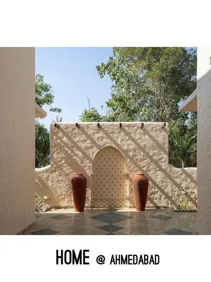 An arched niche with a patterned backdrop creates an artistic focal point in this courtyard. The play of sunlight and shadow on the hand-plastered walls changes throughout the day, adding a dynamic quality to the space.