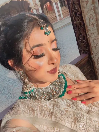 A close-up of a high-glam photoshoot look. This features dramatic winged eyeliner, full lashes, and a bold matte lip, paired with an intricate hairstyle and heavy jewelry for a stunning result.