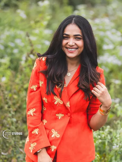 A beautiful smiling shot of the client in her unique bee-embroidered suit.