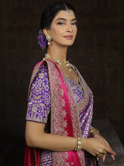 A side profile showing the elegant low bun adorned with purple flowers, tying the whole look together.