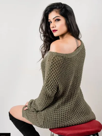 A classic fashion portrait from the 'Attitude on Fleek' series. The model sits looking over her shoulder, her pose exuding confidence and style in a sweater dress and boots.