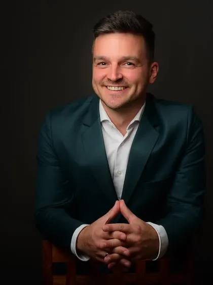 A seated portrait with hands clasped. This pose suggests thoughtfulness and confidence, making it a strong choice for a leadership profile.