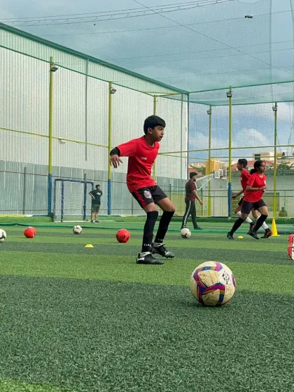 A young player practices dribbling and ball control during a grassroots development session.
