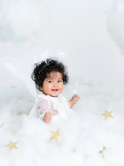 A happy angel playing with a star in her cloud kingdom. This shot captures the playful side of our dreamy, heaven-themed sitter sessions.