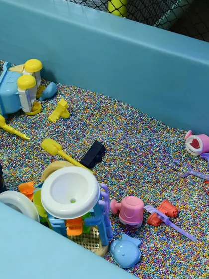 A close-up of our unique sensory pit. It provides all the fun of a sandbox without the mess, filled with colorful grains and beach-style toys.