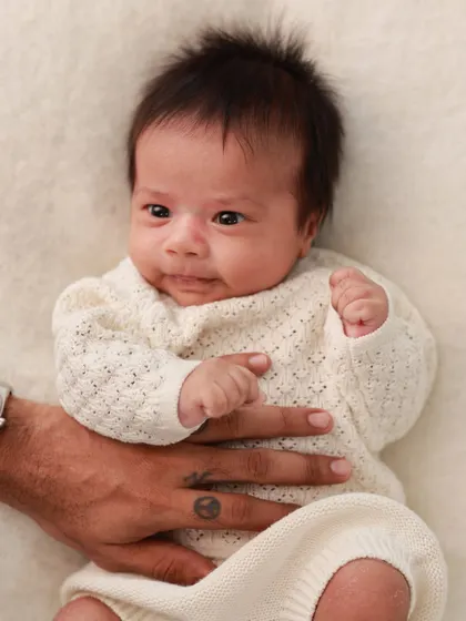 A father's hand gently rests on his newborn's tummy. A simple, loving gesture that speaks volumes.