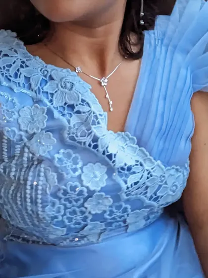This sky blue party wear gown features delicate lace and 3D floral details. It's a beautiful and feminine choice for a daytime event or an evening party.