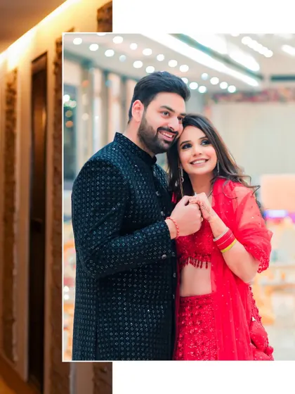 A sweet, candid moment of the couple holding hands. The bride's bright red lehenga and the groom's classic black sherwani are a perfect match.