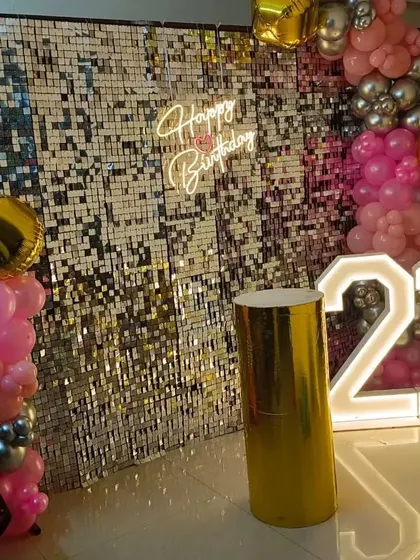 A glamorous 21st birthday with a gold sequin wall, pink balloon accents, and marquee numbers.