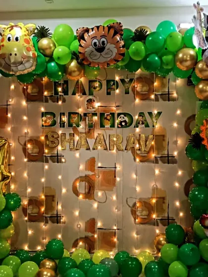A simple and fun jungle animal theme for a 4th birthday at home. This setup includes a balloon arch with animal foil balloons and a light-up backdrop for a festive feel.