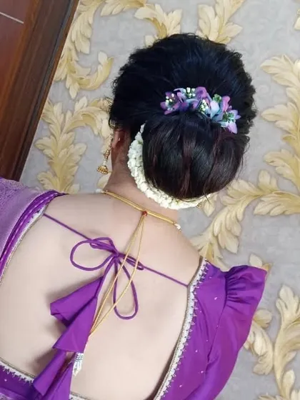 A close-up of the elegant bun, showing the detail of the floral accessory and the neatness of the updo.